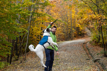 Fototapeta premium happy white dog with owner in autumn forest