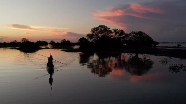 Pescadores Remando al Atardecer en Una Cienaga