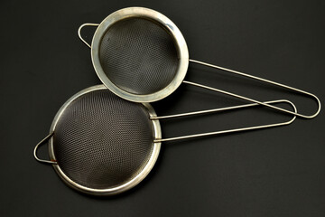 Two stainless steel strainers are a kitchen tool used to separate solids from liquids.