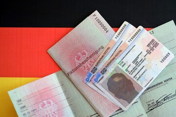 German Permanent resident card and temporary document lies on Germany flag close up. Aufenthaltstitel and Fiktionsbescheinigung