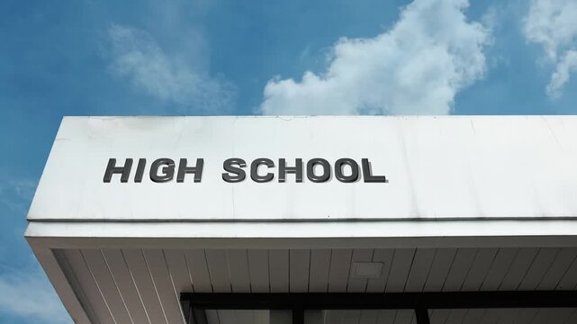 High School word sign clearly displayed on the educational institution facade beneath a clear blue sky, signifying a secondary school for students typically aged 14 to 18, preceding higher education.