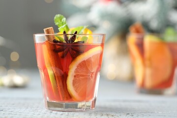 Tasty punch drink in glasses on white wooden table against background with blurred lights, space for text. Bokeh effect