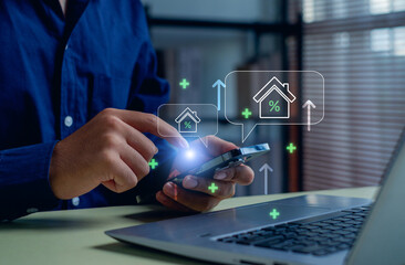 businessman using a smartphone to analyze real estate investment and mortgage interest rates with digital house icons, representing property market growth and financial technology.