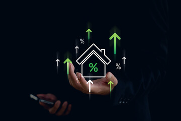 Businessman holding smartphone and digital house icon with percentage and green upward arrows, symbolizing real estate investment, mortgage rate growth, and housing market finance.