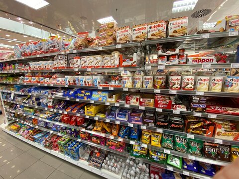 Palma, Spain - October 16, 2025: Colorful display of various snack products on supermarket shelves, featuring popular brands like Nutella, Snickers, and Duplo in a vibrant retail environment