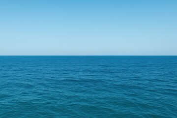 Obraz premium Calm waters stretch endlessly under a bright blue sky on a peaceful day. The soft waves gently ripple, reflecting the serenity of the expansive seascape at midday