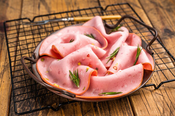 Mortadella sausage slices with pistachios for sandwiches in steel tray. wooden background. top view