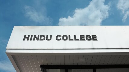 Hindu College word sign clearly displayed on the educational institution facade beneath a clear blue sky, signifying a higher learning center associated with Hindu philosophy, culture, or governance.