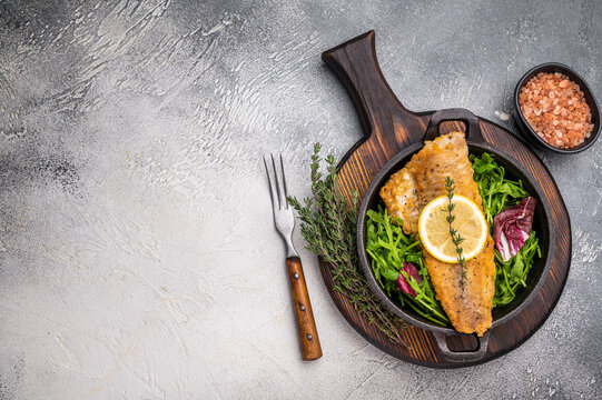 Fried Haddock fish fillet in a pan. grey background. top view