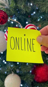 Holiday E-commerce Concept: Hand Holding "Online" Note on Festive Christmas Tree