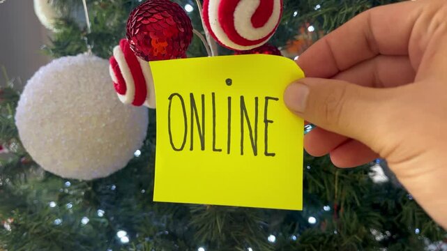 Holiday Business Concept: Hand Holding "Online" Note on Festive Christmas Tree