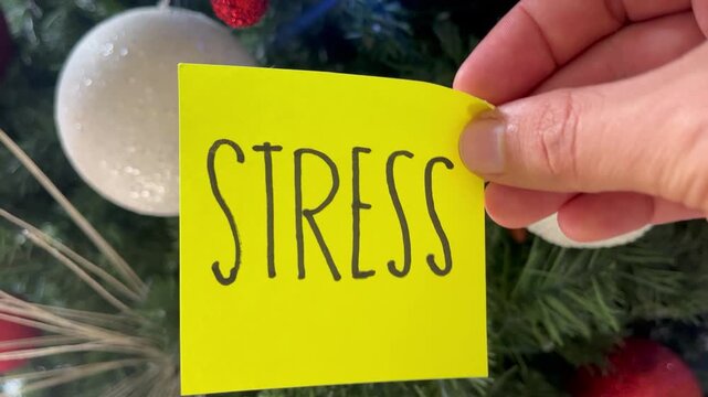 Holiday Stress Concept: Hand Holding "Stress" Note on Festive Christmas Tree