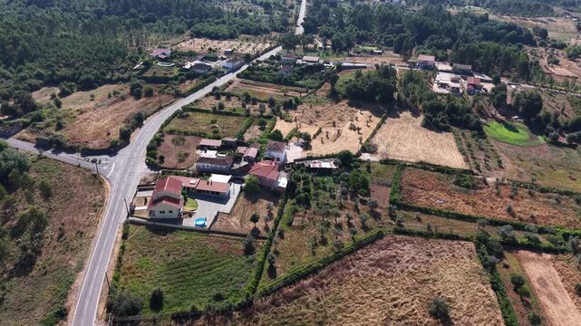Aerial perspective of a village with visible land parcels, roads, houses, and cultivated fields. 