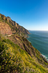 Breathtaking coastline view along Chapman&rsquo;s Peak Drive near Hout Bay, Cape Town, Western Cape; rugged cliffs, blue ocean, winding road, iconic South African landscape under clear sky.