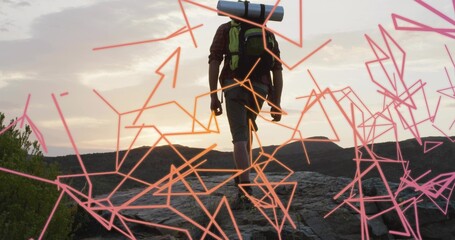 Climbing male hiker wearing hiking boots on rocky ridge at dawn, with backpack, neon lines