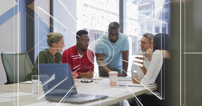 Colleagues leaning over laptop and papers discussing project plans in meeting room, with interface