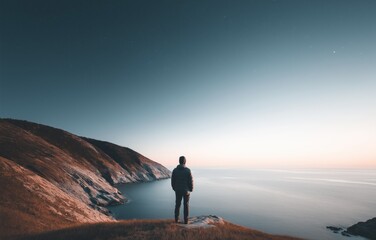 Fototapeta premium Lone figure embracing infinity at tranquil horizon under soft twilight glow over serene ocean vista