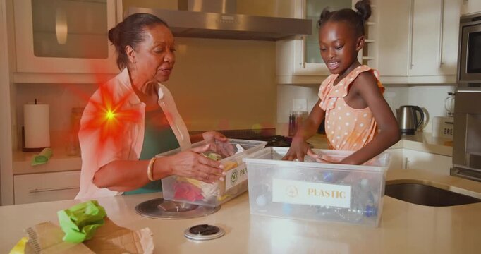 Granddaughter sorting plastic for recycling from bin, clapping for high-five, grandma sorting paper