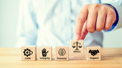 Hand placing wooden block with scales of justice icon