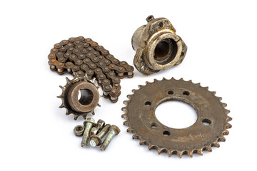 A close-up of a dirty, oily, and greasy chain, sprockets, and wheel hub on an old motorcycle against a white background. The image captures the essence of repair and maintenance.