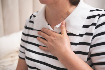 Portrait of adult woman with hand on heart area suffering from chest pain at home.