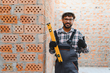 Construction worker holding spirit level giving thumbs up