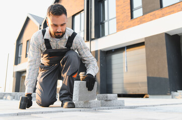 Construction worker installing paving stones for new driveway