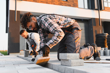 Construction workers installing pavers for new driveway