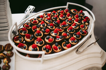 Platter of cookies decorated with berries. The tray is full. It gives a feeling of abundance.