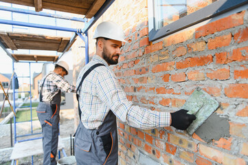 Construction workers laying bricks, building exterior wall