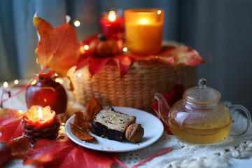 Seasonal tea break with homemade cake surrounded by fall decor and cozy lights.