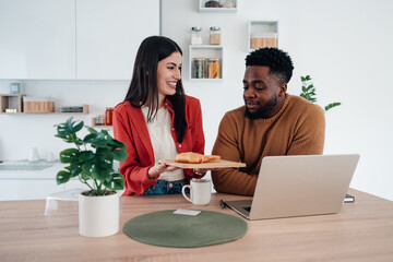 Diverse couple having breakfast while working at home