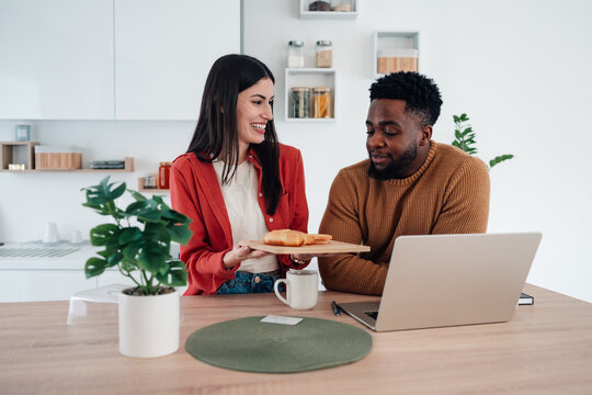 Diverse couple having breakfast while working at home - Powered by Adobe