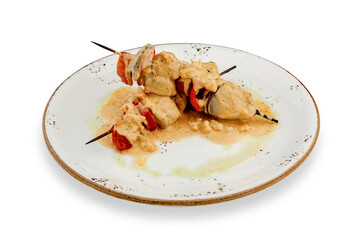 Delicious grilled chicken kebabs with bright bell pepper on a rustic dish, drizzled with cream sauce. isolated.
