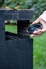 A woman throws trash into a trash can, caring for the environment, garbage disposal