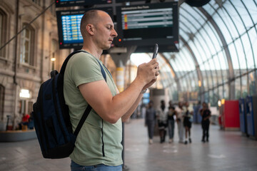 Tourist is using smart phone and smiling in airport or train station