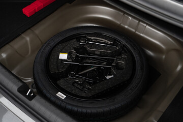 Spare tire in car trunk. A new tire. Changing a tire on the road, preparing for a trip, a serious incident. Car maintenance.