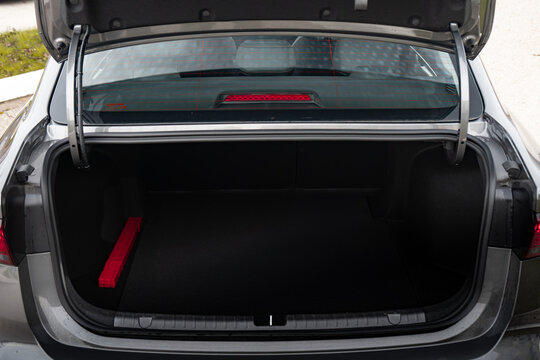 The big black empty trunk of SUV car with rubber mat and a tool box. Open luggage carrier of car closeup