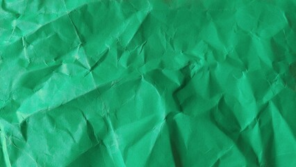 Recycled wrinkled green paper background texture. Crumpled and rough green paper surface close up.