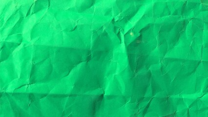 Crumpled recycled green paper background texture. Wrinkled and rough green paper surface detail.