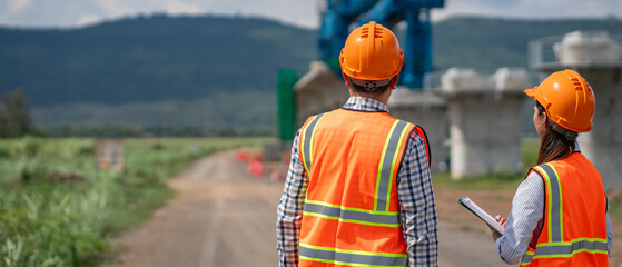 Civil engineers use surveying tools and a theodolite to measure and reference road construction plans during the ongoing project.