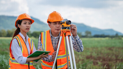 Civil engineers use surveying tools and a theodolite to measure and reference road construction plans during the ongoing project.
