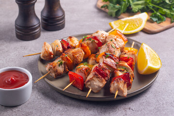 Delicious grilled chicken skewers with capsicum, lemon, salad and ketchup on a plate over the table. Chicken kebab. Healthy food concept.