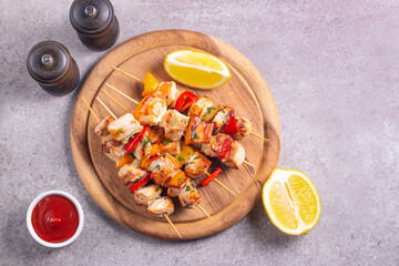 Delicious grilled chicken skewers with capsicum, lemon, salad and ketchup on a plate over the table. Chicken kebab. Healthy food concept.