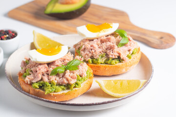 Two delicious tuna open sandwiches with avocado and boiled eggs. Tuna toast.