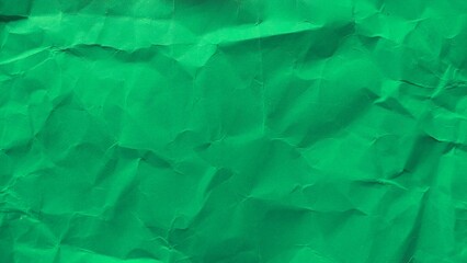 Crumpled green recycled paper surface texture. Wrinkled and folded green paper background detail.