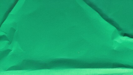 Green crumpled paper surface texture with wavy folds. Wrinkled green paper background with copy space for text.