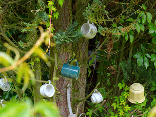 Various mugs and a flower pot hanging on a tree.