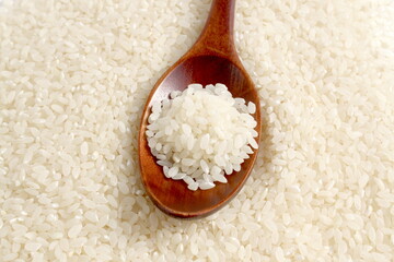 Texture rice cereal lies on a flat surface with a wooden spoon.	