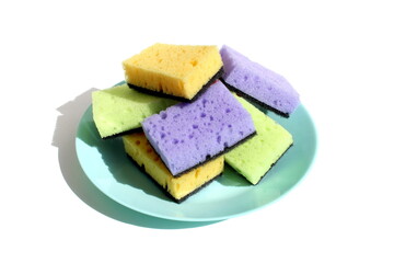 On a white background, there are many rectangular dishwashing sponges lying on a plate.